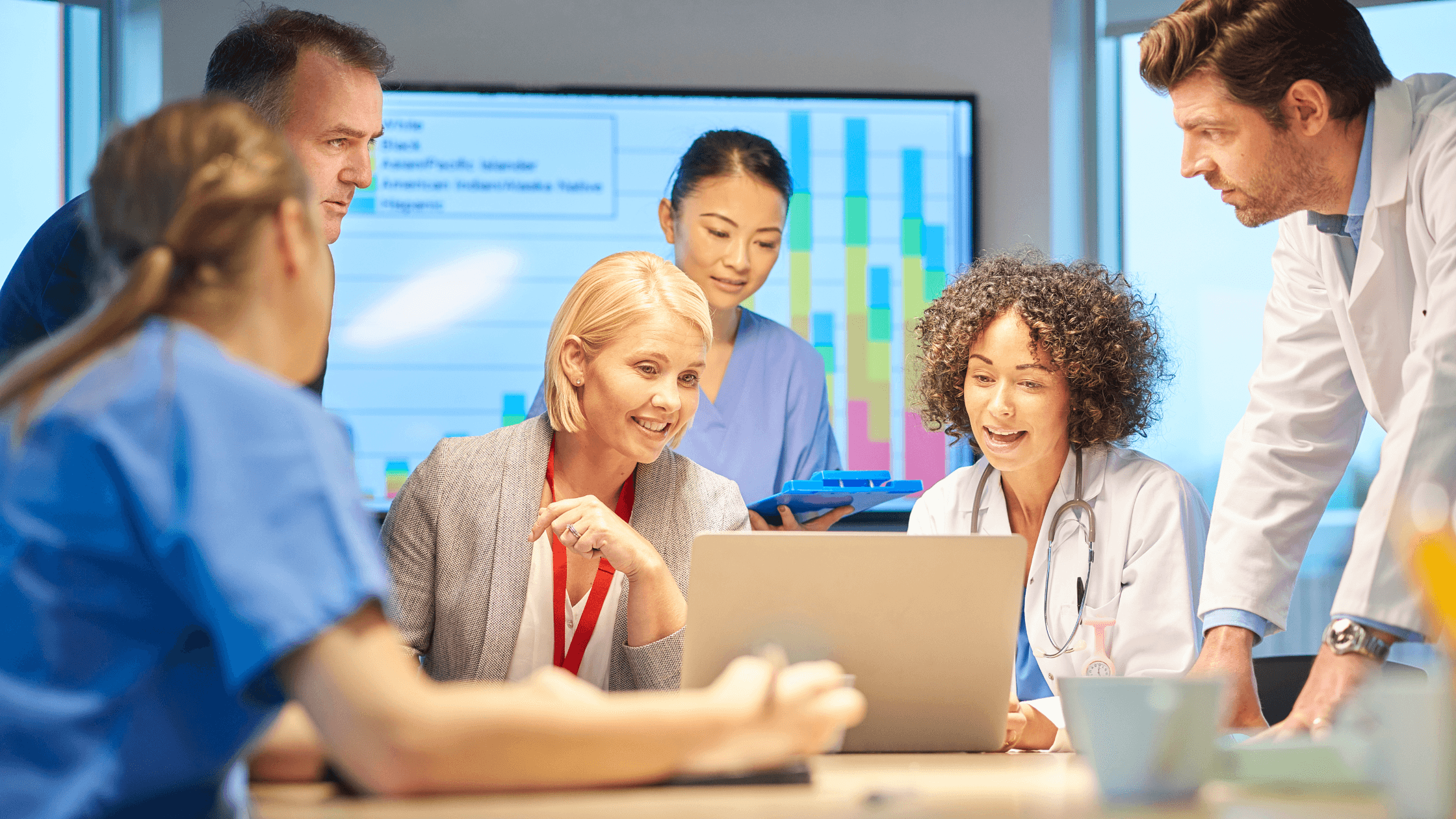 Team of doctors and nurses gather around a computer