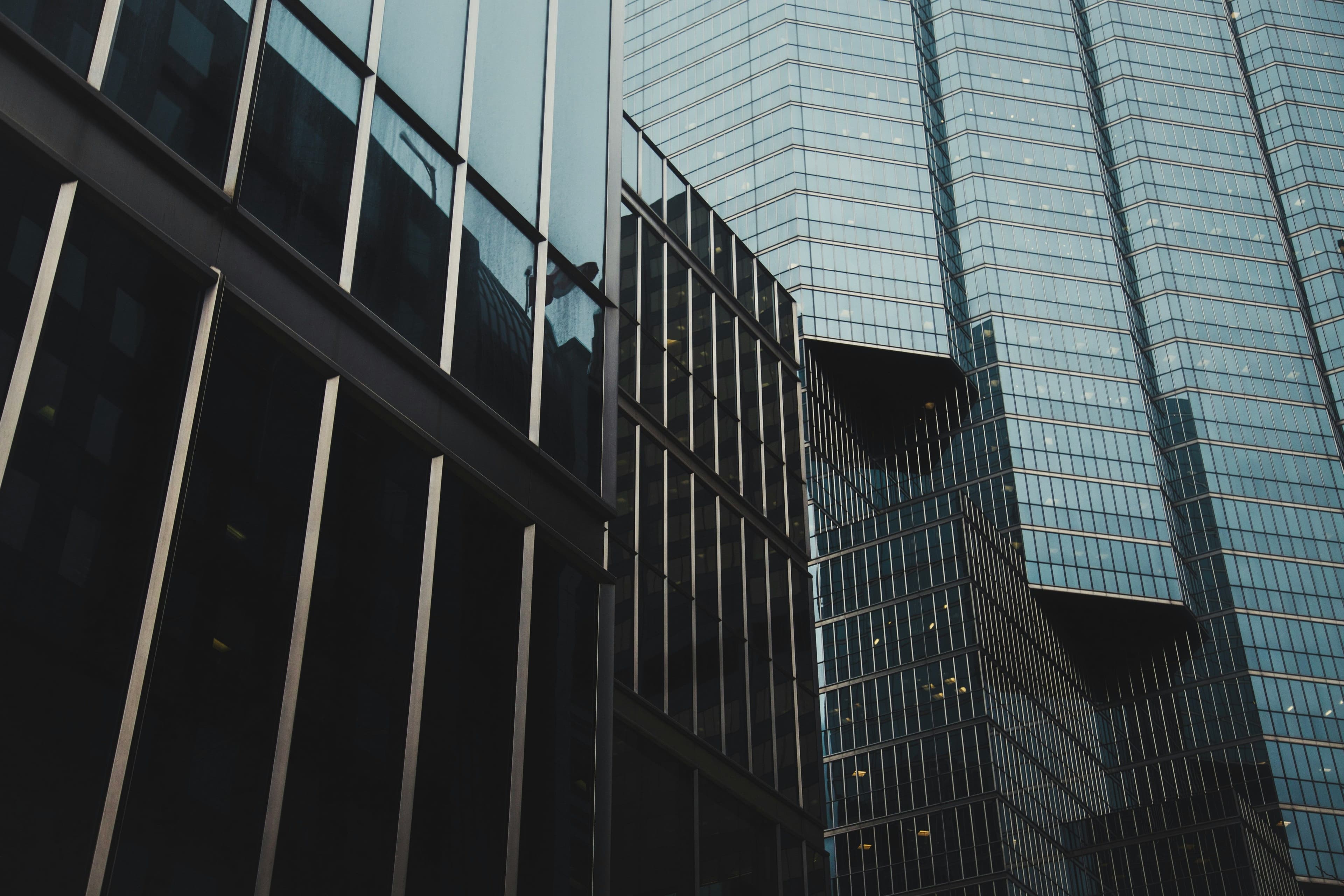 Modern skyscrapers with reflective glass facades, showcasing geometric patterns and sharp angles against a clear sky.